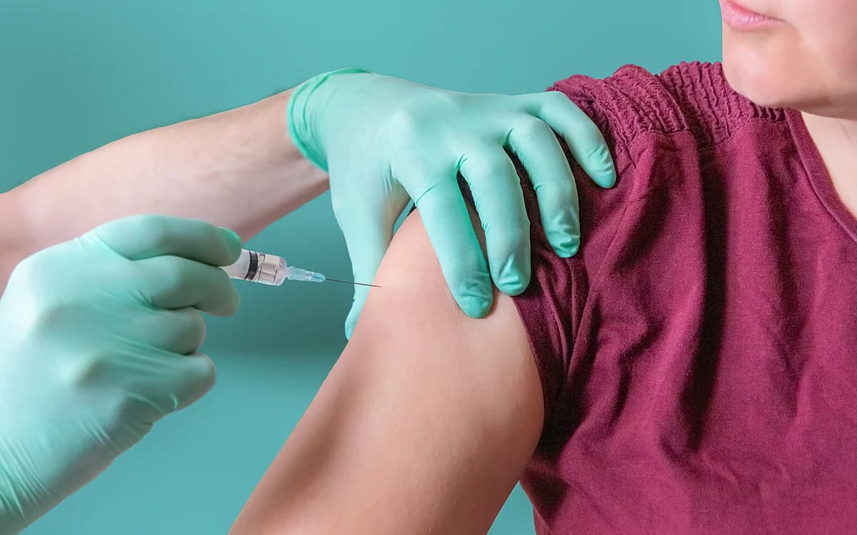 Injection vaccinale réalisée à la seringue dans l'épaule d'un patient
